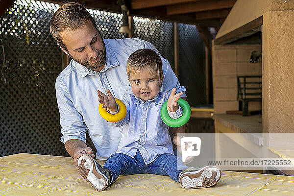 Süßer Junge spielt mit Ringen auf dem Tisch vor dem Vater im Hinterhof