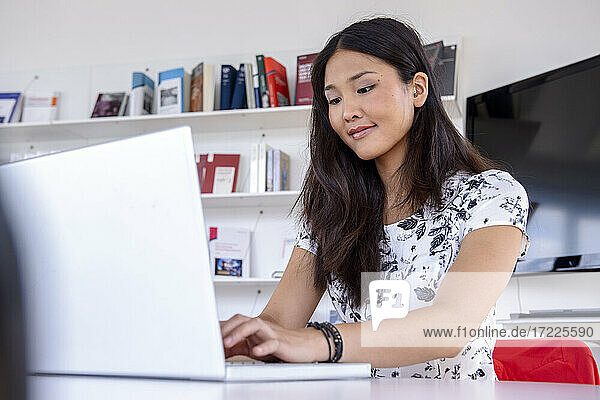 Junge Frau arbeitet am Laptop in einer Bibliothek