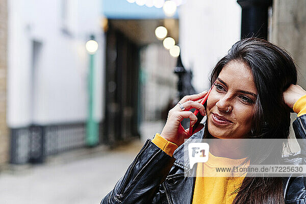 Lächelnde Frau  die in der Stadt mit einem Mobiltelefon spricht