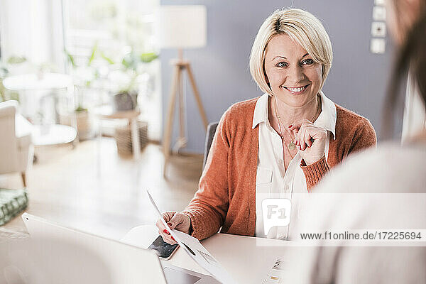 Lächelnde Unternehmerin  die einen Kollegen bei der Arbeit zu Hause ansieht