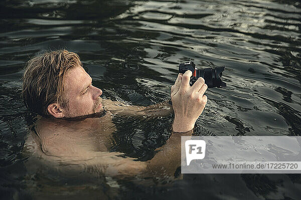 Mann schwimmt im See  macht Fotos mit seiner Kamera