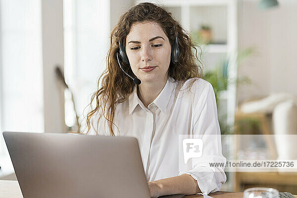 Beautiful female customer service representative using laptop at home office