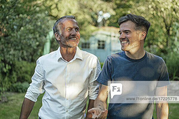 Lächelnder Sohn  der mit seinem wegschauenden Vater im Garten diskutiert