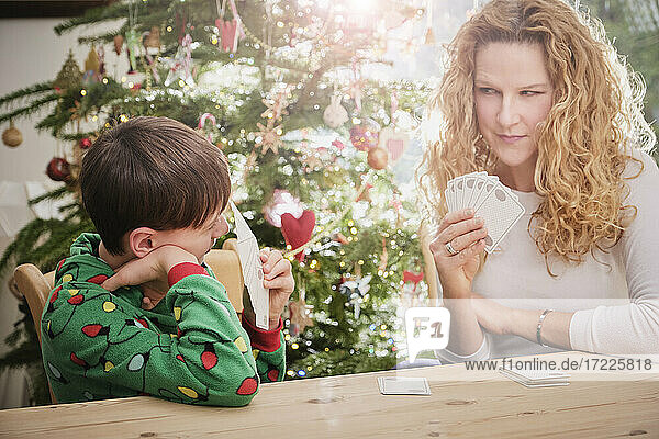 Mutter und Sohn spielen zu Weihnachten Karten am Tisch