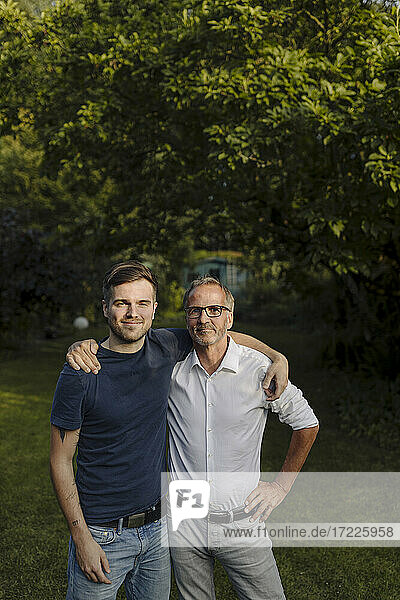 Son and father with arm around standing in back yard