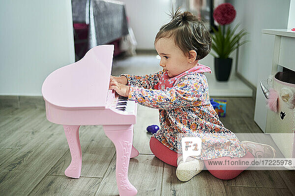 Baby spielt Klavier  während es zu Hause auf dem Boden sitzt