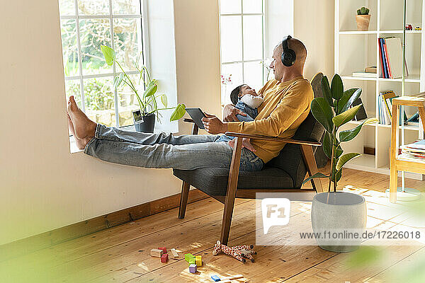 Vater sieht seine Tochter an  während er zu Hause über Kopfhörer Musik hört