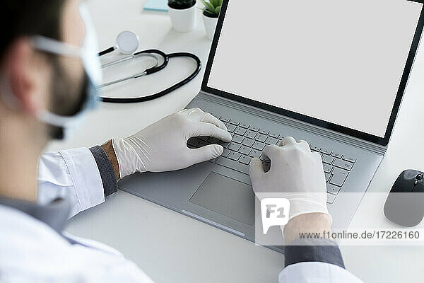 Male health care doctor using laptop in hospital during COVID-19