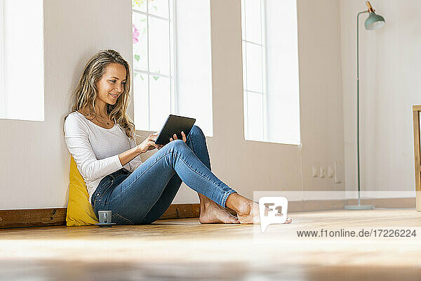 Lächelnde schöne Frau  die ein digitales Tablet zu Hause benutzt