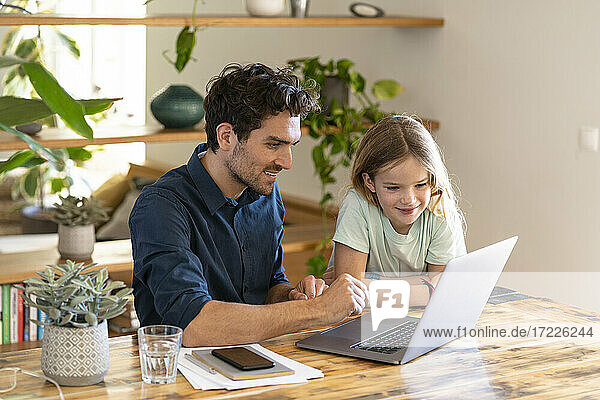 Happy father and daughter looking at laptop