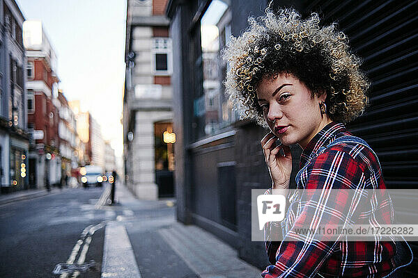 Curly haired young woman in front of shutter