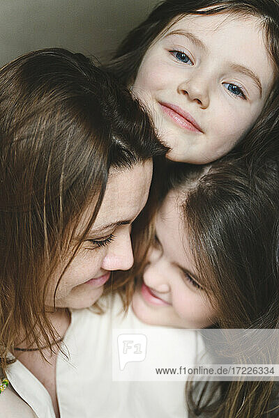 Smiling mother and daughters together at home