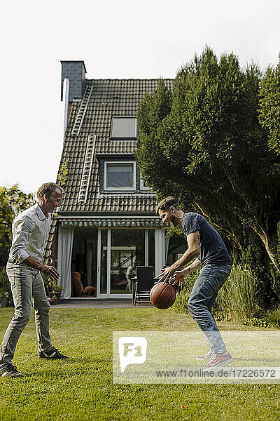 Verspielter Vater und Sohn mit Basketball im Hinterhof