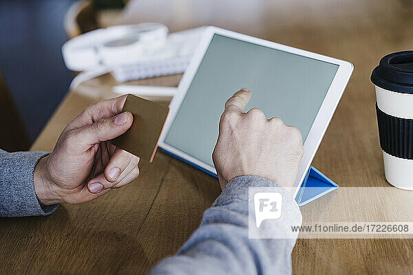 Geschäftsmann mit Kreditkarte und digitalem Tablet auf dem Schreibtisch am Arbeitsplatz