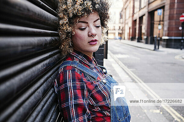 Curly haired woman with eyes closed leaning on shutter