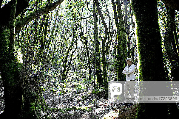 Mature man with arms crossed standing by tree in Garajonay National Park  La Gomera