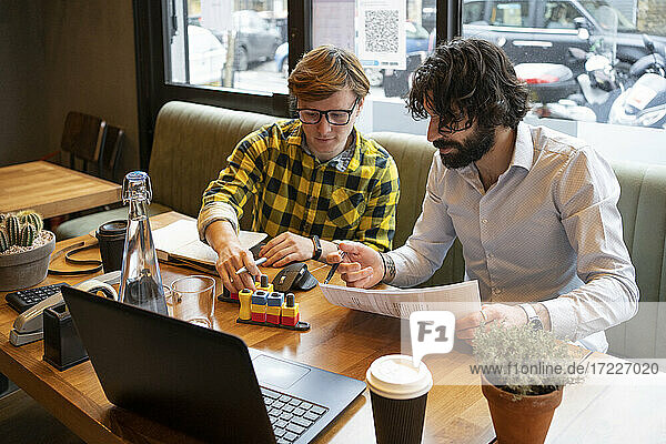 Businessmen discussing over 3D printing game while working at coworking office