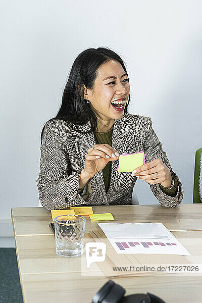 Happy businesswoman with adhesive note at office