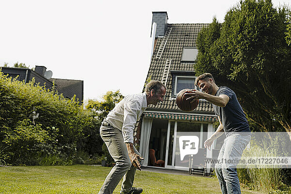 Sohn spielt Basketball mit Vater im Hinterhof