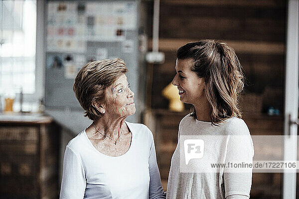 Curious senior woman looking at smiling granddaughter at home