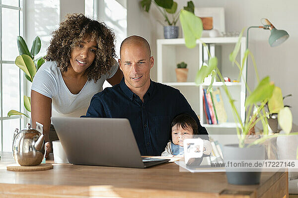 Mutter  Vater und Tochter schauen zu Hause auf den Laptop