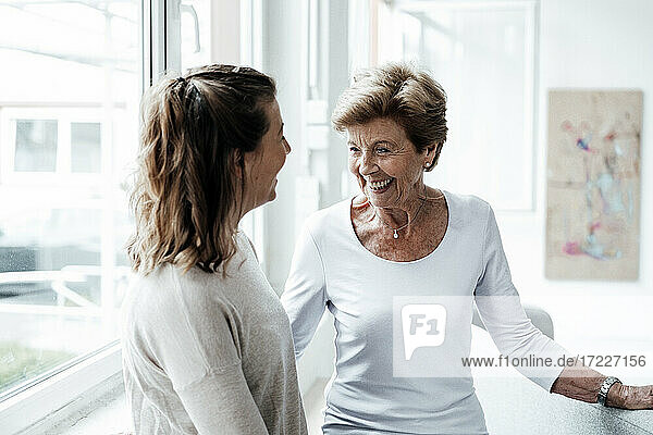 Fröhliche Großmutter  die eine junge Frau zu Hause anlächelt
