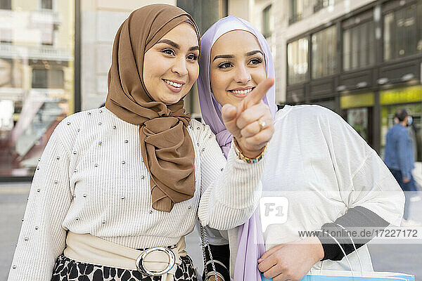 Young Arab woman pointing by female friend in city