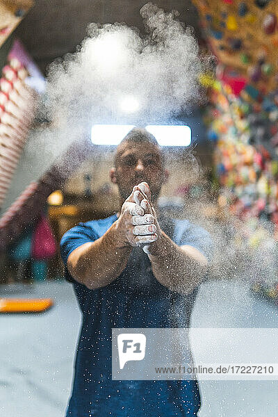 Young sportsman dusting talcum powder on hands in health club