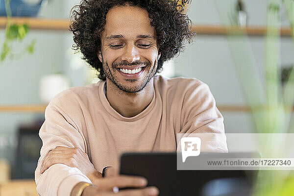 Gut gelaunter männlicher Unternehmer  der zu Hause ein digitales Tablet benutzt