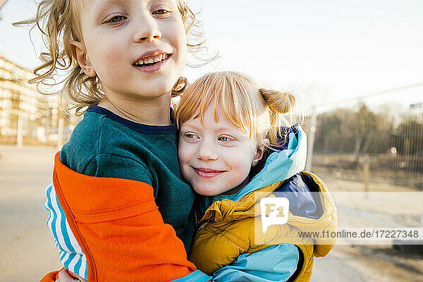 Lächelnder Junge umarmt süße Schwester