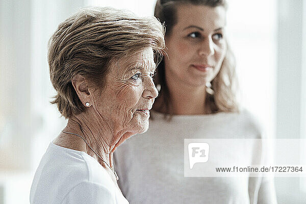 Ältere Frau schaut weg  während sie bei ihrer Enkelin zu Hause steht