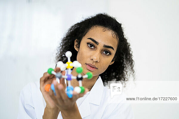 Young researcher holding molecular structure in laboratory