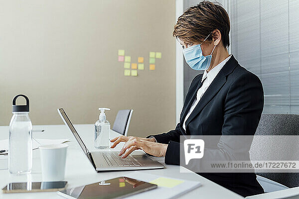 Geschäftsfrau arbeitet am Laptop am Schreibtisch während COVID-19 im Büro