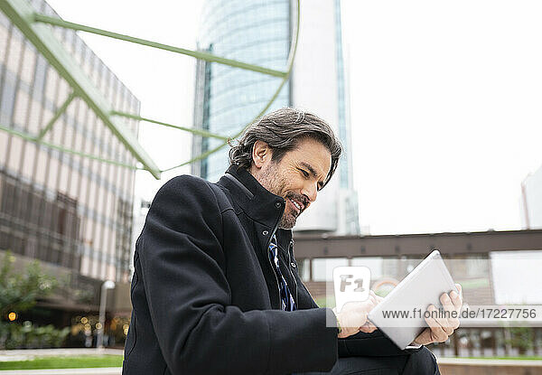 Lächelnder Geschäftsmann mit digitalem Tablet im Büropark