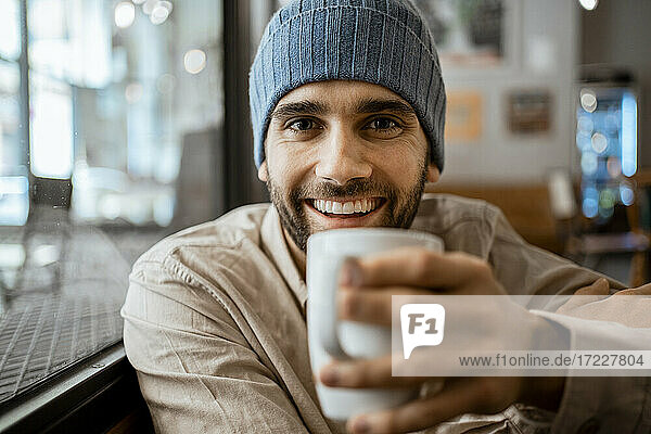 Glücklicher erwachsener Mann mit Kaffeetasse in einem Cafe