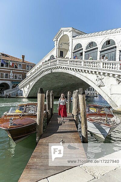 Junge Frau mit rotem Kleid an einem Steg mit Booten  Canal Grande  Rialto Brücke  Venedig  Venetien  Italien  Europa