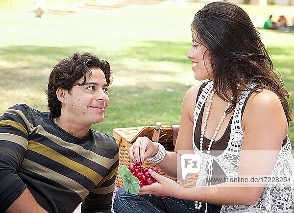 Attractive hispanic couple having a picnic outdoors in the park