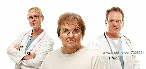 Besorgte ältere Frau mit Ärzten hinter isoliert auf einem weißen Hintergrund