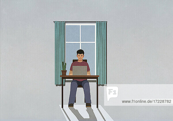 Mann arbeitet von zu Hause aus am Laptop im Fenster