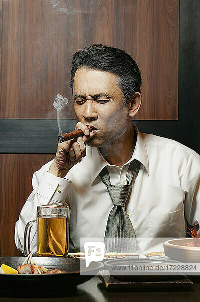 Geschäftsmann raucht Zigarre beim Mittagessen im Restaurant
