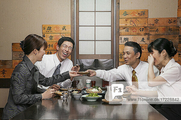 Glückliche japanische Geschäftsleute genießen Sushi Mittagessen im Restaurant