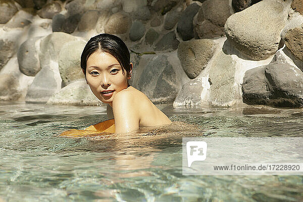 Porträt schöne junge Frau schwimmen in sonnigen Pool