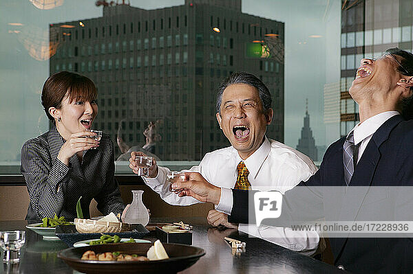 Glückliche Geschäftsleute lachen beim Mittagessen im Hochhausrestaurant