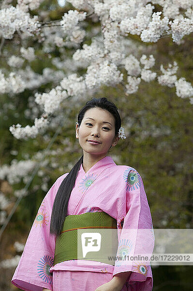 Porträt schöne junge Frau im Kimono unter Kirschblüten