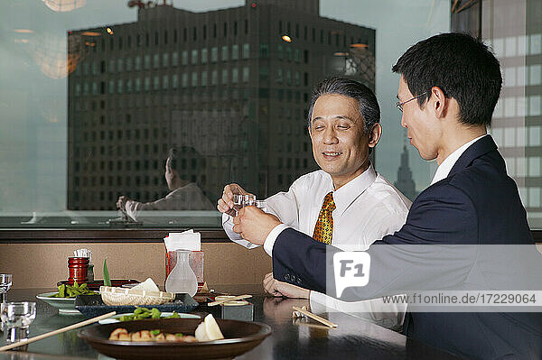 Japanische Geschäftsleute beim Mittagessen in einem Hochhausrestaurant