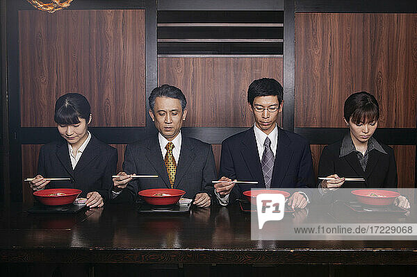 Japanische Geschäftsleute essen mit Stäbchen im Restaurant