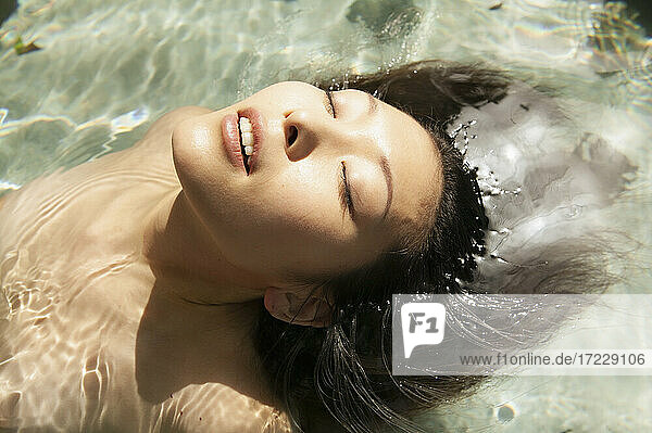 Close up schöne heitere junge Frau schwimmt in sonnigen Pool