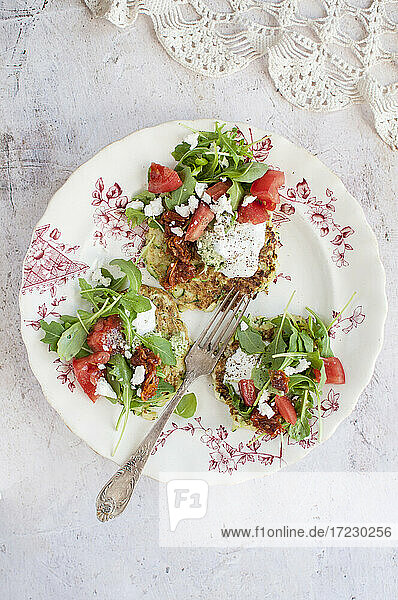 Courgette cakes topped with cream  tomato  arugula and feta cheese