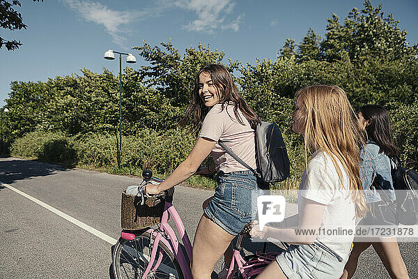 Weibliche Teenager Radfahren auf der Straße während sonnigen Tag