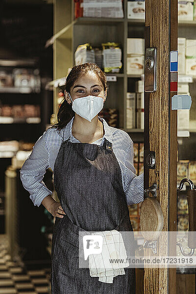 Weibliche Besitzerin mit Hand auf der Hüfte im Geschäft während COVID-19